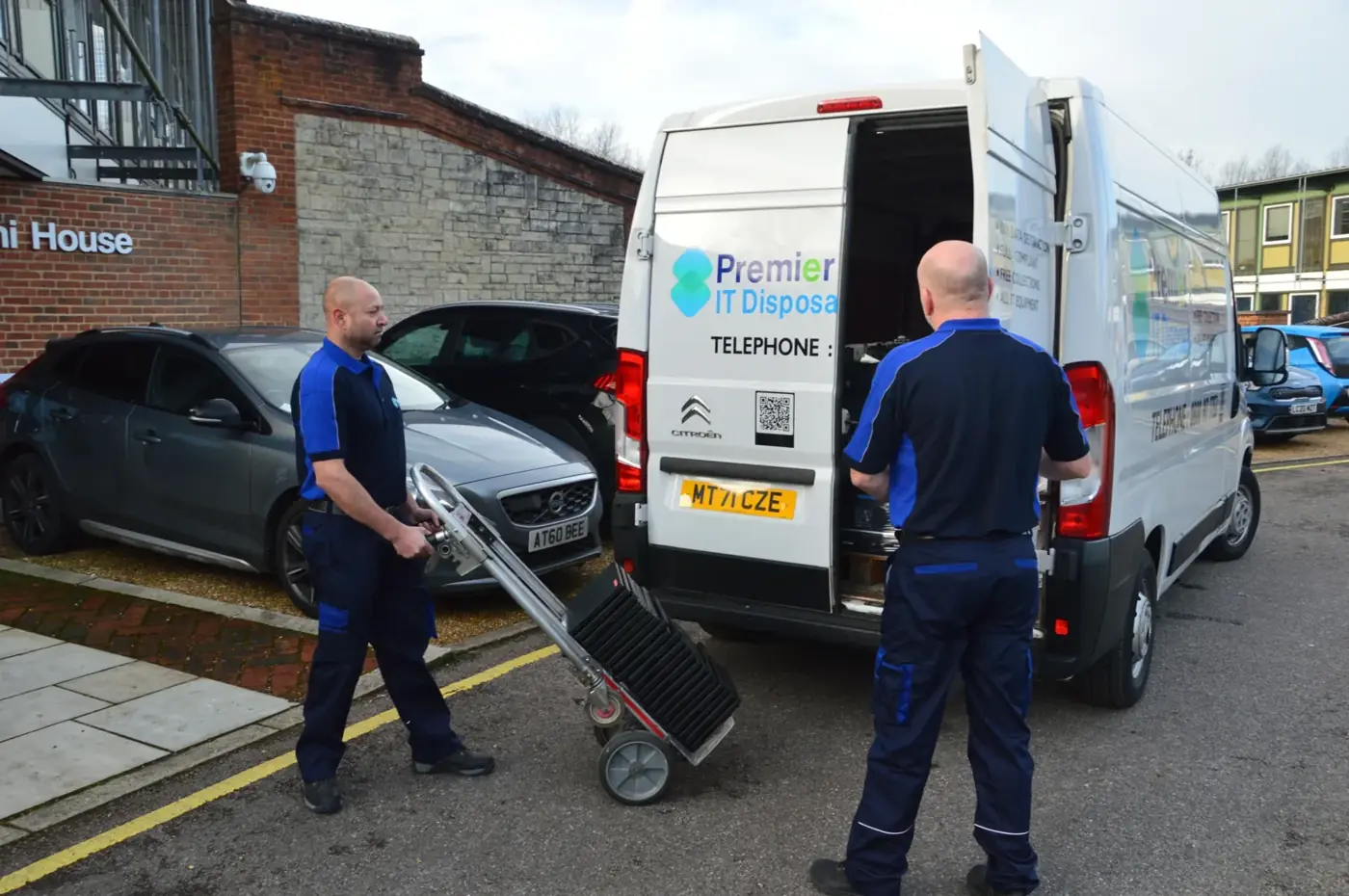 Premier IT Disposal employees recycling computers with branded van